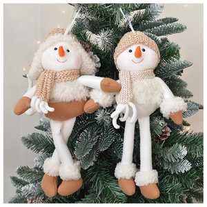 Detail of plush snowman Christmas ornaments in off-white and brown on tree branches
