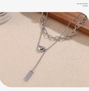 Close-up of double layer stainless steel necklace with lucky bean pendant and toggle detail