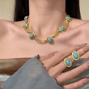 Detail of vintage gold necklace and rings set with turquoise stones on a model