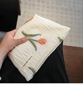 Detailed view of white pleated canvas makeup bag with orange tulip embroidery design