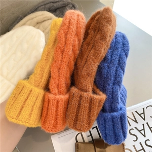 Close-up of thick cable knit texture on beanie hats in five various warm colors