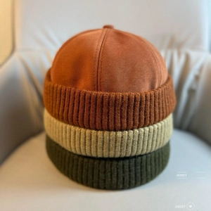 Detail of docker hats in rust, beige, and olive green with ribbed knit texture and twill fabric