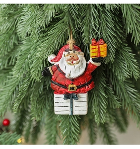 Detailed view of resin Santa Claus ornament hanging on a green Christmas tree branch