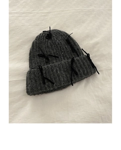 Detailed view of dark grey knit beanie with delicate black ribbon bow accents