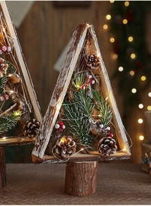 Detail of wooden Christmas tree with LED lights, pine cones, and red berries on a base