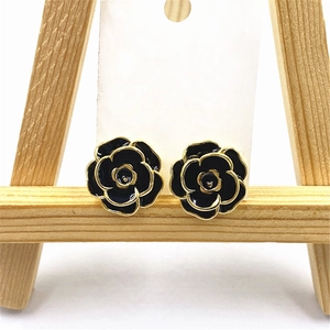 Macro detail of black enamel rose stud earrings with golden edges on display