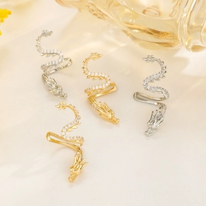 Elegante Drachen-Ohrclips in Gold und Silber mit Zirkonia auf Seidenhintergrund
