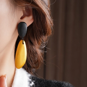 Detailed close-up of a model wearing minimalist black and yellow teardrop earrings