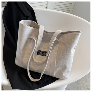 Detail view of the oatmeal canvas tote bag texture with fashion label on modern chair