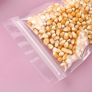 Clear plastic resealable food storage bag for dried corn with zip lock on pink background