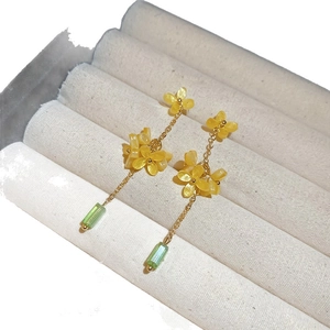 Handmade floral earrings with yellow petals and green resin beads on a display