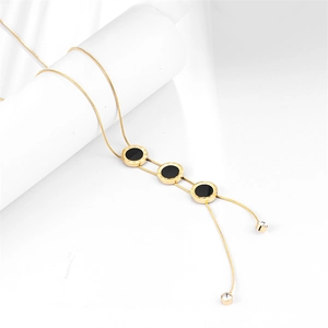 Golden snake chain necklace featuring three black circular pendants with Roman numerals