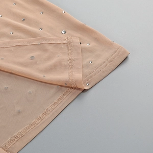 Macro shot of nude mesh fabric with silver rhinestones and fine stitching detail