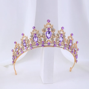 Detail of baroque gold crown with large purple teardrop crystals and sparkling white rhinestones