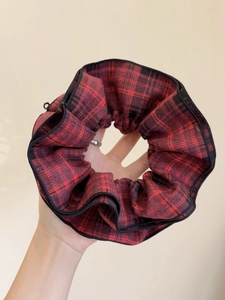 Close-up of red and black tartan fabric hair scrunchie with soft pleated texture