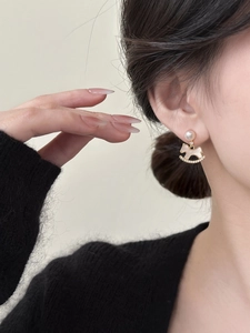 Close-up of elegant gold plated rocking horse earrings with pearls and crystal details