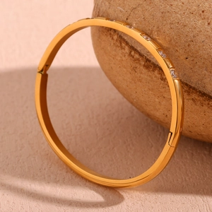 Detailed macro view of 18K gold plated oval bangle with zircon pavé and side clasp lock