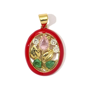Detail of vintage oval pendant with red enamel, gold floral motifs and colorful zircons