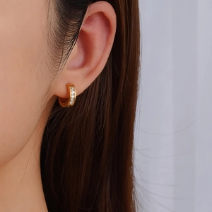 Fashionable gold round stainless steel earrings with cubic zirconia worn on female model
