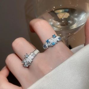 Detail of silver rings with textured finish and blue gemstones on a model hand