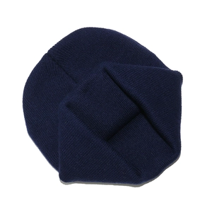 Détail du tissu en maille bleu foncé du bonnet tricoté en vue pliée à plat sur fond