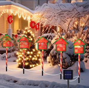 Solar Christmas candy cane garden lights with Santa Stop Here sign in winter snow