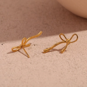 Macro detail of 18K gold plated stainless steel bow earrings with a creative ribbon design