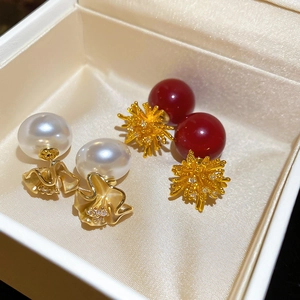 Macro shot of 18k gold plated floral earrings with white pearls and red zircon details