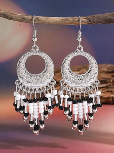 Detailed view of bohemian tassel earrings with hollow silver discs and monochrome beads