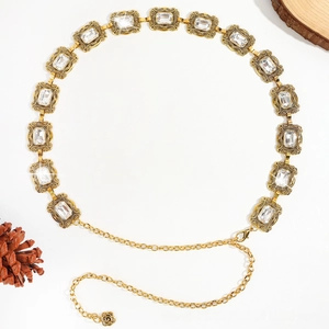 Détail de la chaîne de taille vintage dorée avec cristaux clairs et pendentif floral