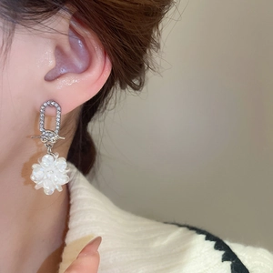 Nahaufnahme eines Models mit silbernen Blumenohrringen mit Perlen- und Diamantakzenten