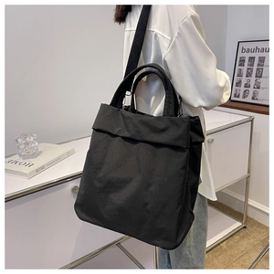 Lifestyle shot of large black nylon tote bag worn by a model in a minimalist interior