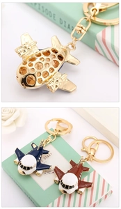 Detail of crystal airplane keychains in gold hollow design and colorful enamel finish