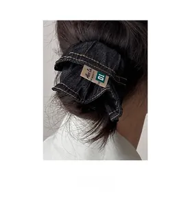 Detail of dark blue denim scrunchie with yellow stitching and vintage industrial label