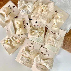 Close-up of lace hair clips and cream bow pins with daisy embroidery and pearls