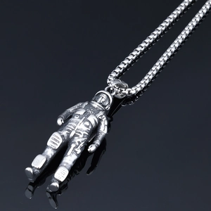 Macro shot of retro silver astronaut pendant on stainless steel box chain necklace