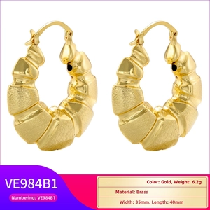 Detail view of chunky gold-plated hollow C-shape earrings with wavy textured brass finish