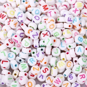 Close-up of bulk white acrylic alphabet beads with colorful letters for DIY jewelry