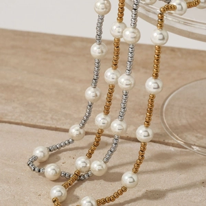 Elegant beaded shell pearl necklace with gold accents on a minimalist stone surface