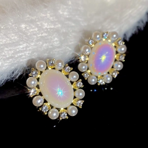 Close-up of vintage oval stud earrings with iridescent opal stones and pearl accents