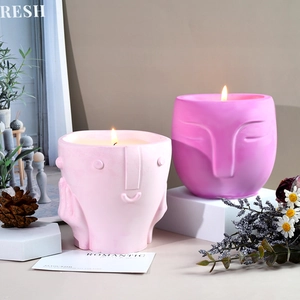 Artistic face-shaped scented candles in matte pink and rose red on geometric stands