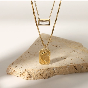 Macro view of gold sun and moon pendant with layered zircon square box chain necklace