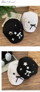 Detail of black and white beret hats featuring star patches and bow tie decorations