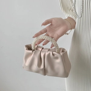 Detail of beige pleated cloud bag with elegant white pearl bead wrist handle
