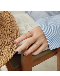 Close-up of minimalist gold twisted rope ring on model with rustic natural background