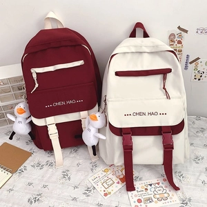 Detail of color-block canvas backpacks with cute duck charms and buckle straps