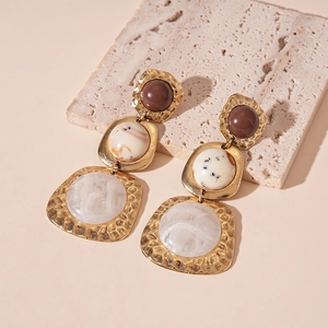 Macro shot of vintage resin earrings with gold-toned metal texture and drop pendants