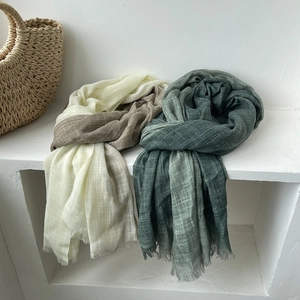 Detail of elegant beige and green cotton linen scarves with fringe and soft texture