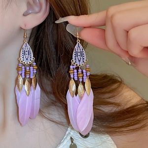 Close-up of bohemian earrings featuring purple beads and soft feathers on a model