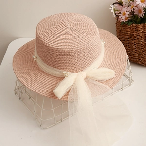 Pink boater straw hat with white lace ribbon and pearl accents for summer sun protection
